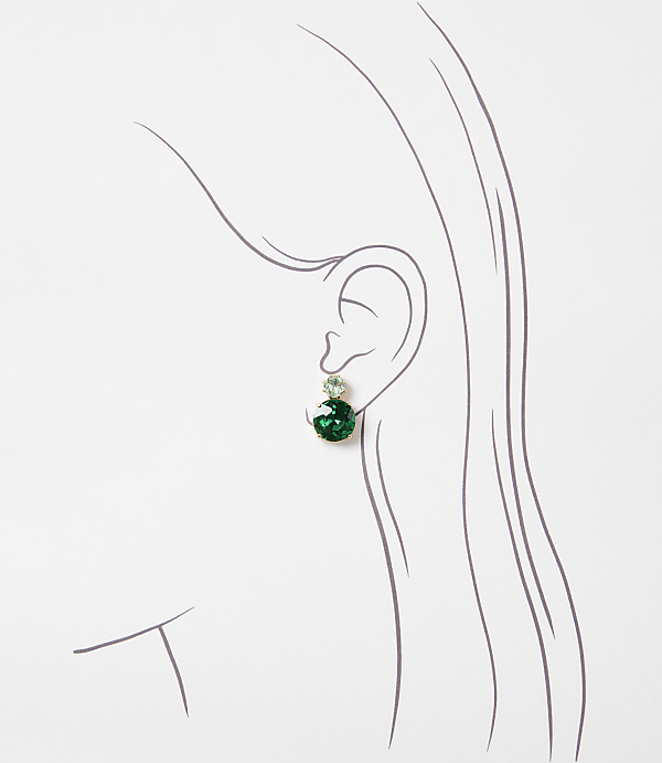 A delicate green earring dangles from a stylized ear against a plain white background.
