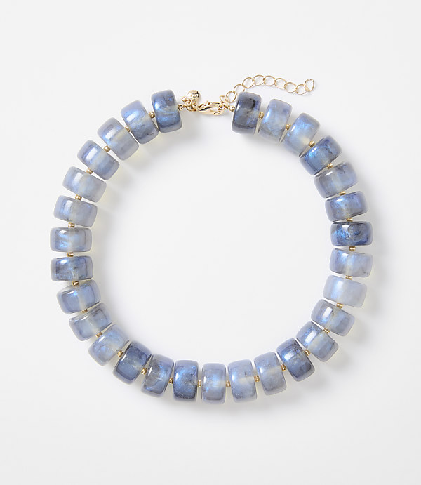 A necklace of blue, translucent, barrel-shaped beads with gold accents is displayed against a plain white background.