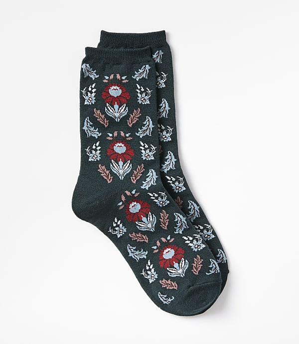 A pair of dark green socks with a floral pattern are laid out against a plain white background.