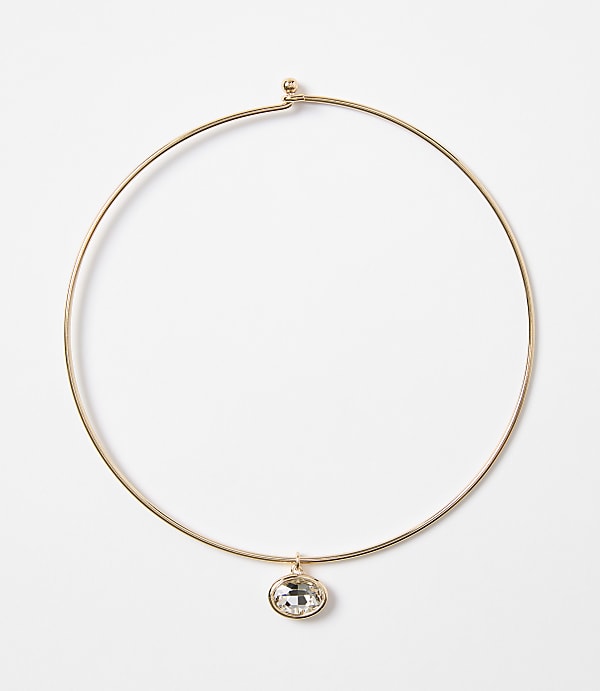 A delicate gold choker necklace with a single oval crystal pendant hangs against a plain white background.