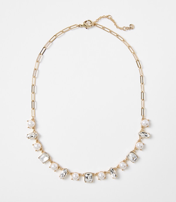 A gold chain necklace with alternating pearls and clear rectangular gems is displayed against a plain white background.