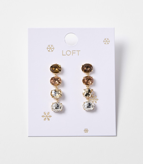 A pair of gold drop earrings with four oval-shaped gemstones in varying shades of brown and clear are displayed on a white card with snowflake accents and the "LOFT" logo.