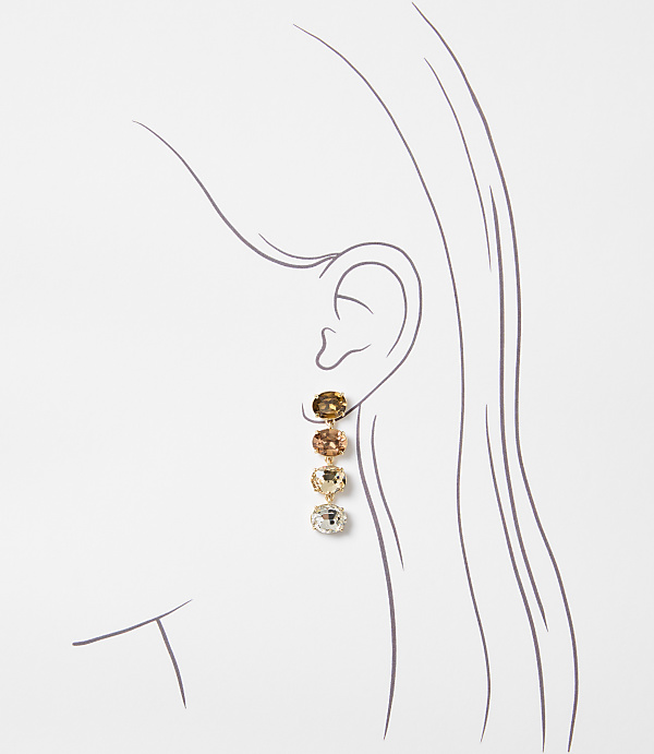 A delicate gold earring with four gradient-colored gemstones hangs from a stylized ear against a plain white background.