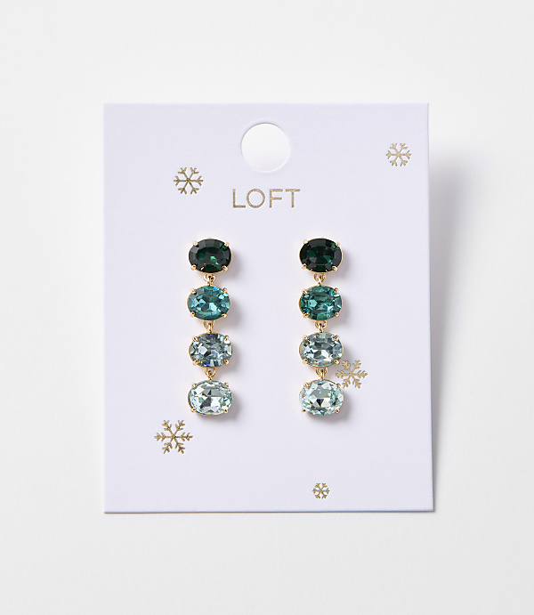 A pair of oval gemstone drop earrings in shades of green and blue hang from a white Loft card adorned with snowflakes.