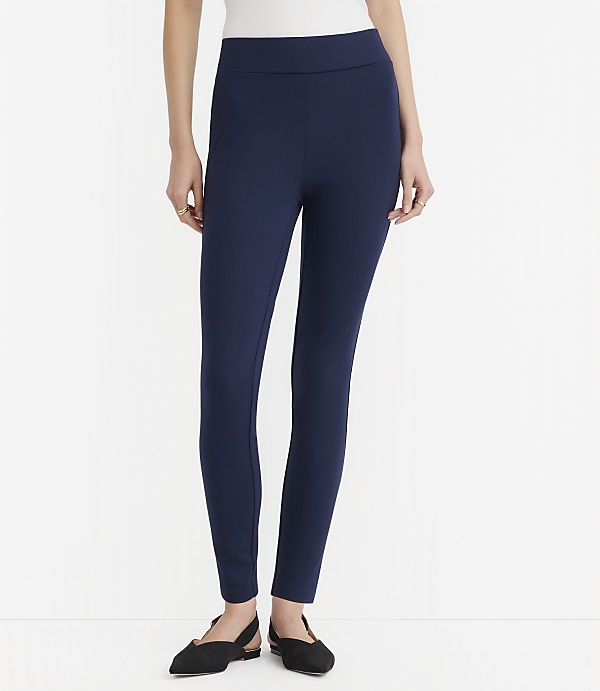 A woman in navy blue leggings and black flats stands against a plain white background.