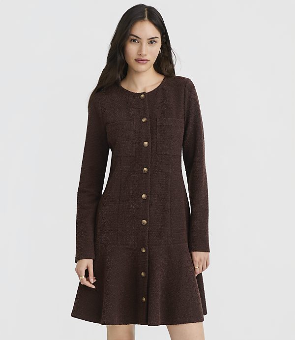 A woman in a brown textured dress with gold buttons stands against a plain gray background.