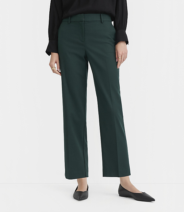 A person in a black top and dark green pants stands on a white floor against a white background.