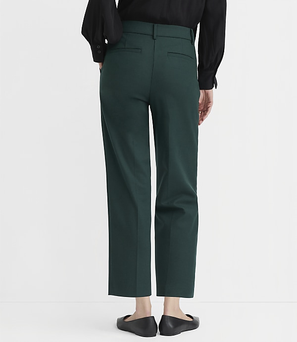 A person wearing a black shirt and dark green pants stands against a plain white background.