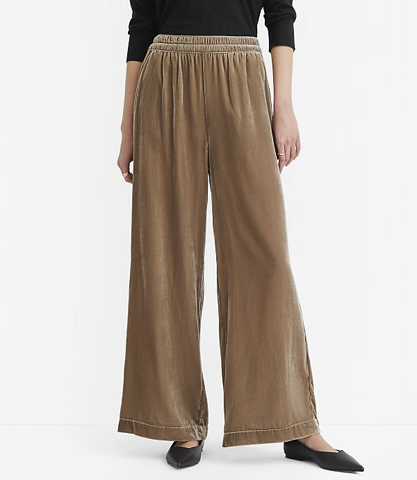 A person wearing wide-leg, taupe velvet pants with a black top stands against a plain white background.