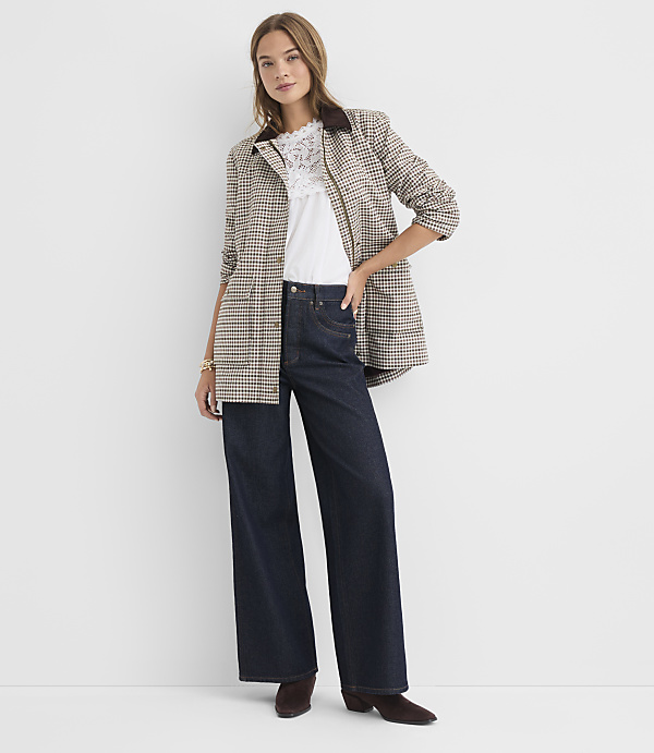 A woman in a plaid jacket and wide-leg jeans stands against a plain white background.
