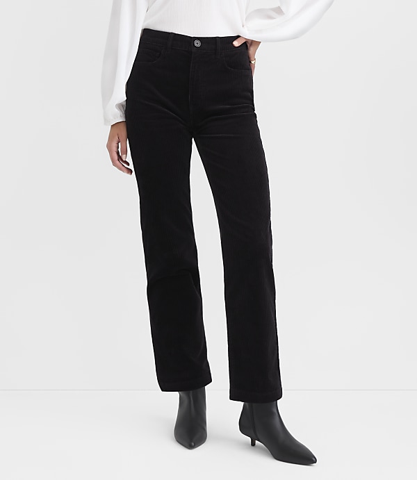 Black corduroy pants and black heeled boots are in the foreground, against a plain white background.