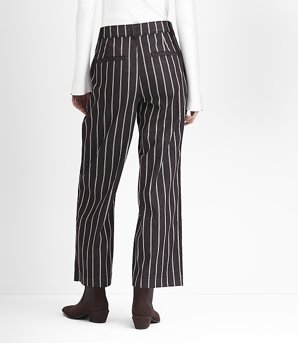 A person wearing pinstripe pants and brown boots stands against a plain white background.