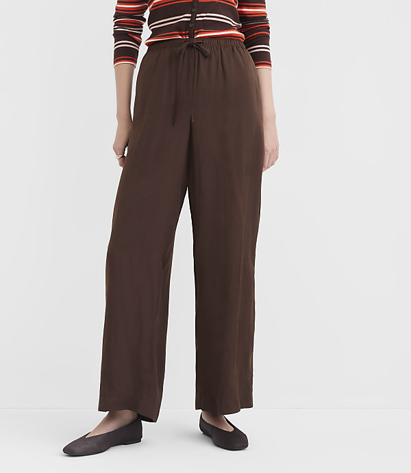 A person stands in brown wide-leg pants and a striped cardigan against a plain white background.