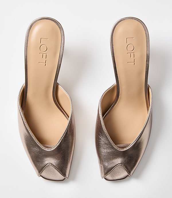A pair of rose gold pointed-toe mules with the "LOFT" logo are displayed against a plain white background.