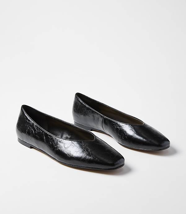 A pair of glossy black square-toe ballet flats rests on a plain white background.