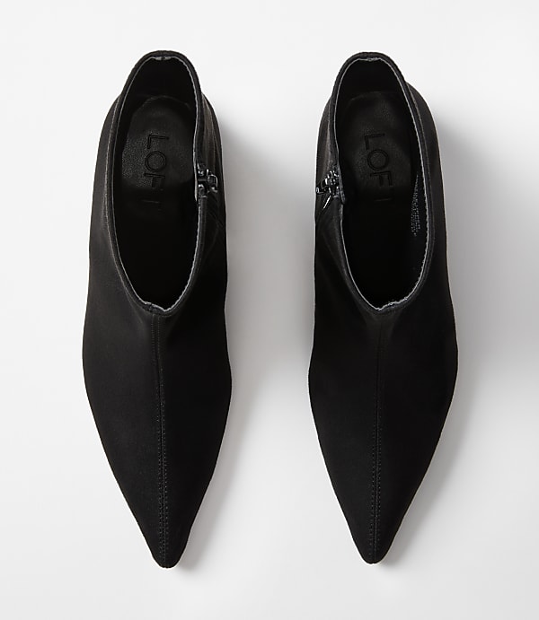 A pair of black pointed-toe ankle boots with zippers are displayed against a plain white background.