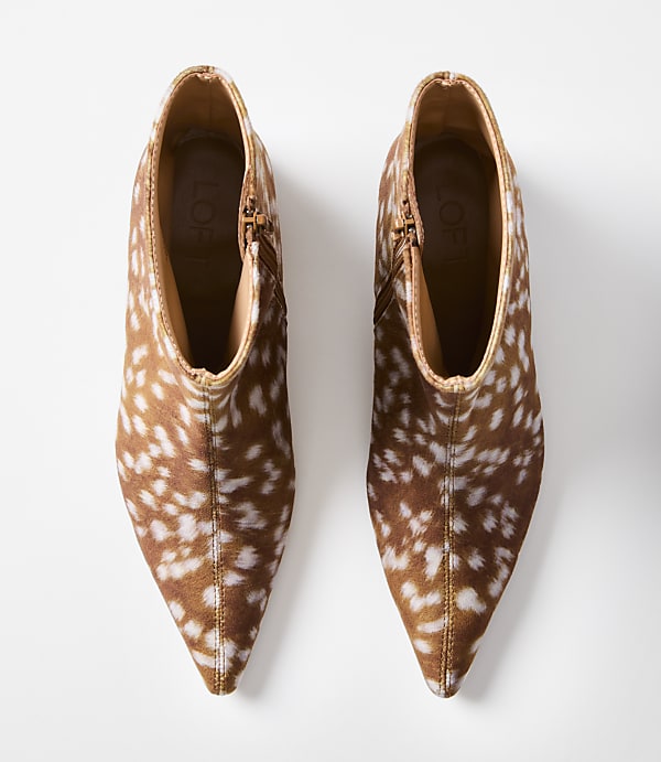 A pair of brown and white spotted ankle boots with pointed toes are displayed against a plain white background.