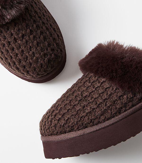 A pair of cozy brown knit slippers with faux fur trim rests on a plain white background.
