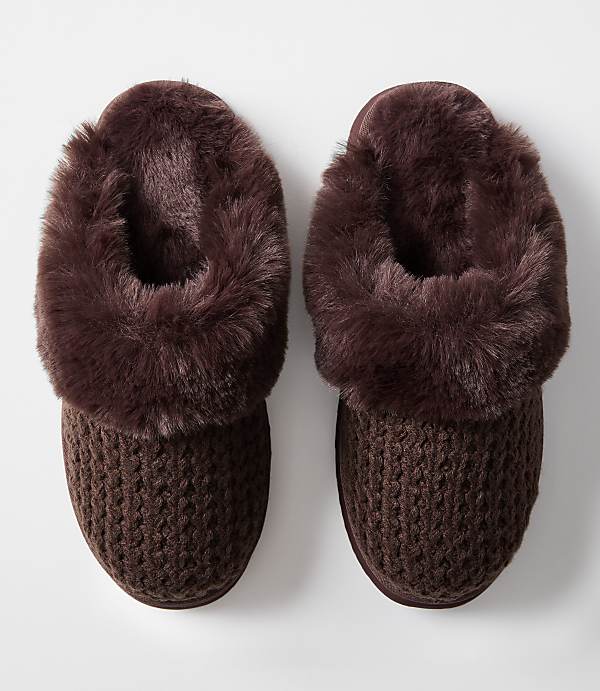 A pair of cozy brown knit slippers with fluffy trim rests on a plain white background.