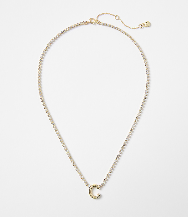 A delicate gold chain with a sparkling pendant in the shape of the letter "C" rests against a plain white background.