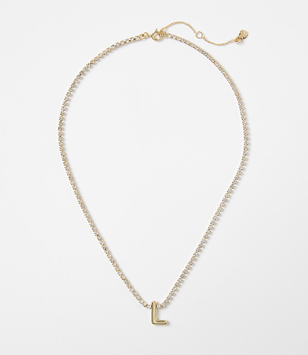 A delicate gold necklace with a sparkling chain and a single letter "L" charm rests on a plain white background.