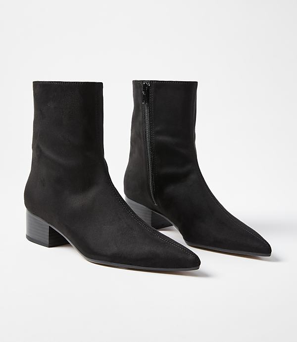 A pair of black pointed-toe ankle boots with block heels are displayed against a plain white background.