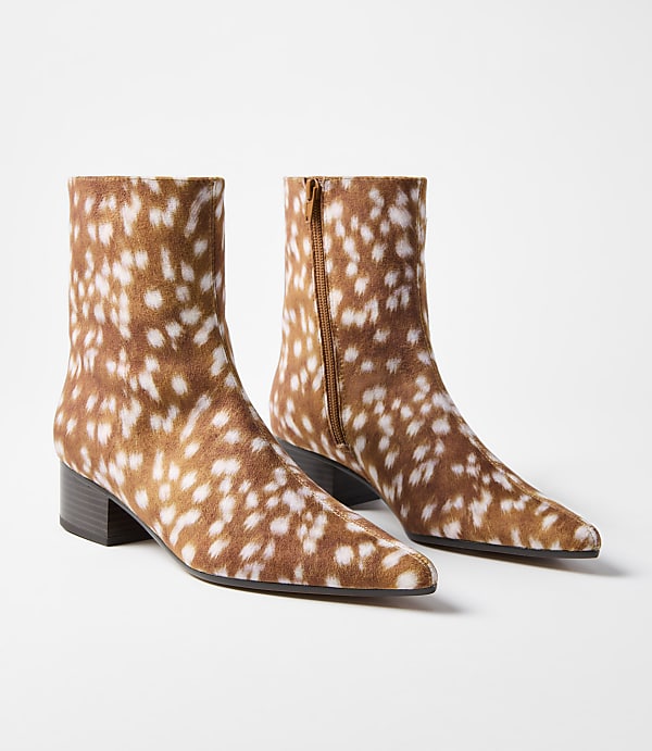 A pair of brown and white spotted ankle boots with low heels are displayed against a plain white background.