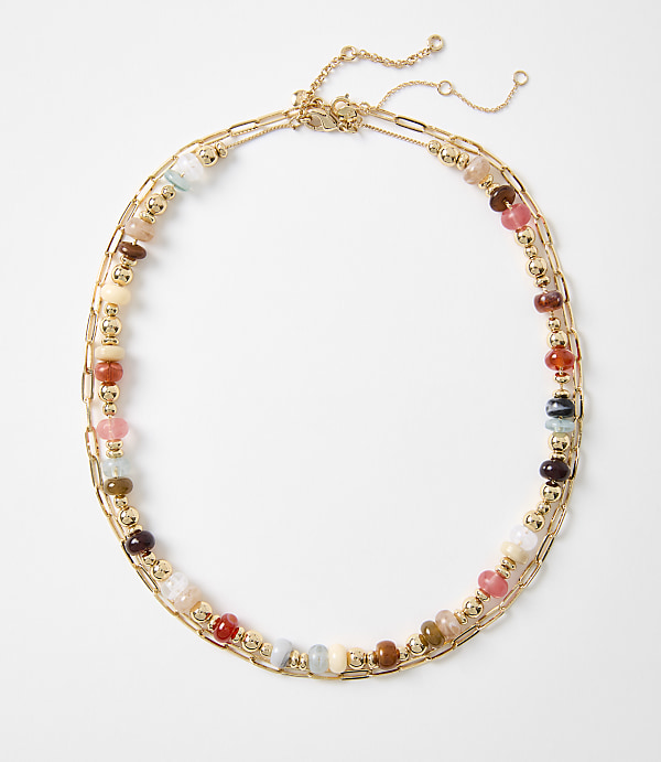 A colorful beaded necklace with gold chain accents lies on a plain white background.