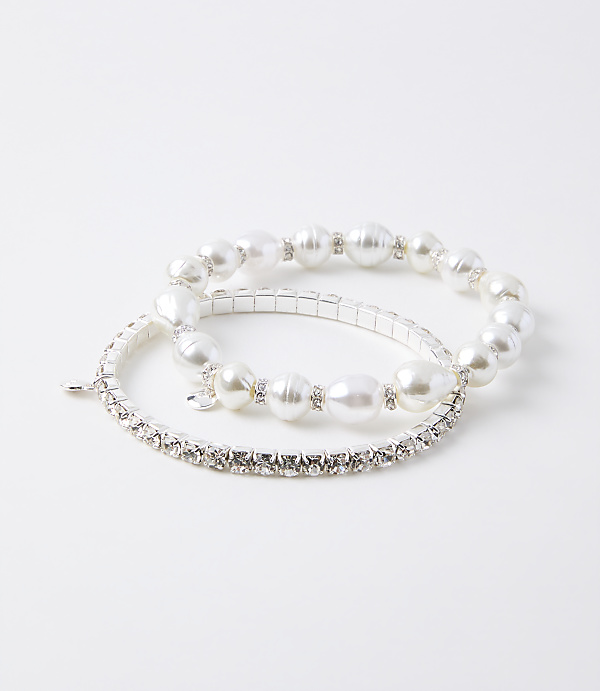 Two bracelets, one with pearls and rhinestones and another with only rhinestones, rest on a plain white background.