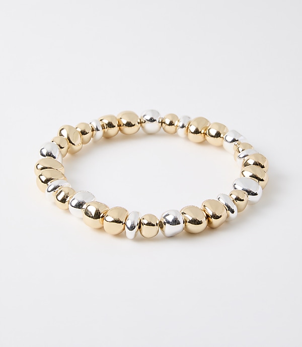 A bracelet of mixed gold and silver beads rests on a plain white background.