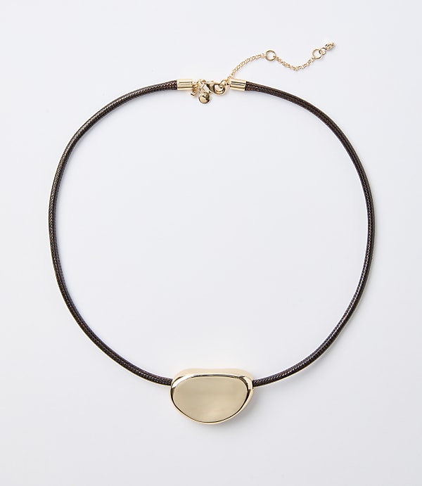 A dark brown cord necklace with a smooth, gold-toned pendant rests on a plain white background.
