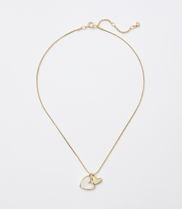 A delicate gold chain necklace with a heart-shaped pearl and a small gold heart charm hangs against a plain white background.