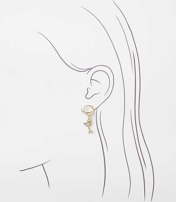 A delicate gold earring shaped like a martini glass with a green gem hangs from a stylized ear against a plain white background.
