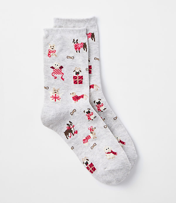 A pair of light gray socks with a pattern of festive dogs wearing sweaters and scarves, along with dog bones and presents, are laid out against a plain white background.