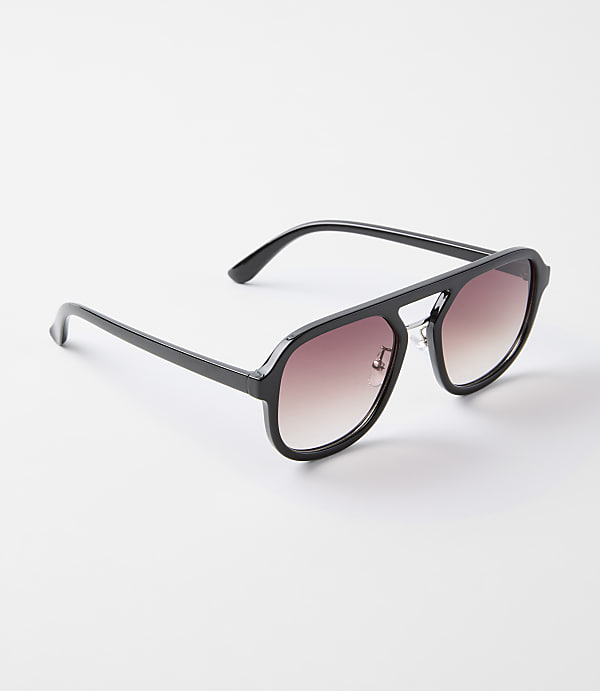 A pair of black aviator sunglasses with gradient lenses rests on a plain white background.
