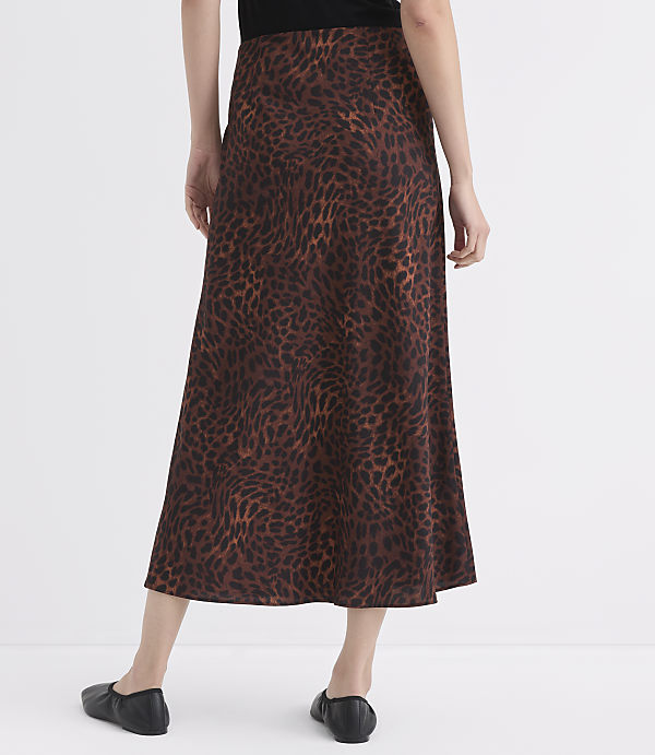 A person wearing a brown leopard-print skirt and black flats stands against a plain white background.