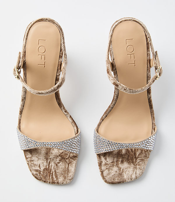 A pair of beige velvet sandals with rhinestone embellishments on the toe strap and ankle strap are displayed against a plain white background.