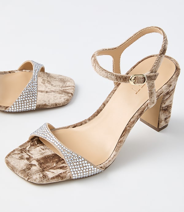 A pair of crushed velvet block heels with rhinestone straps are displayed against a plain white background.