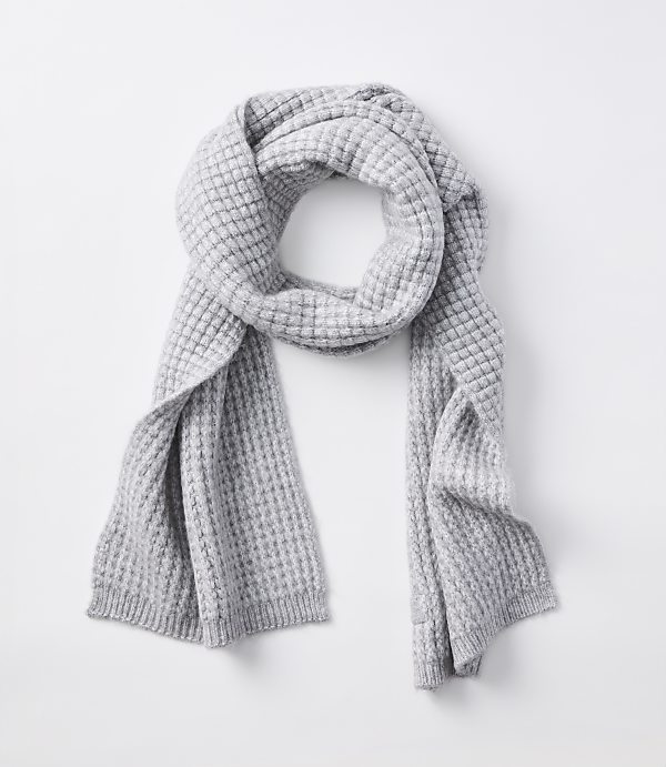 A light gray waffle-knit scarf is draped over a plain white background.