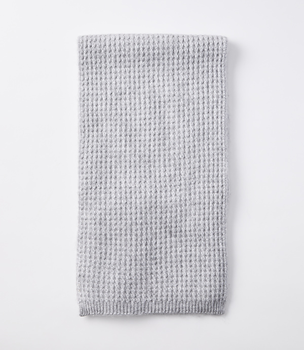 A folded light gray waffle-knit blanket rests on a plain white background.
