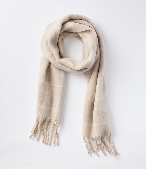 A soft, beige plaid scarf with fringed ends lies draped against a plain white background.
