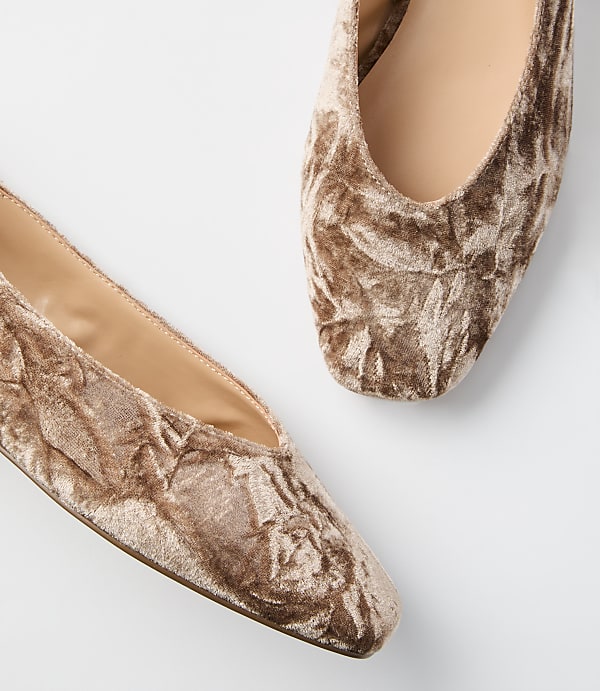 Two crushed velvet ballet flats in a light brown hue are arranged on a plain white background.