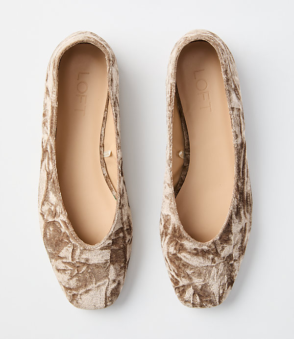 A pair of crushed velvet ballet flats with "LOFT" branding rests on a plain white background.