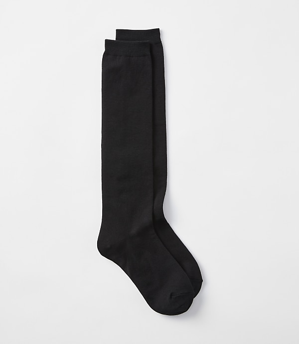A pair of black knee-high socks lies on a plain white background.