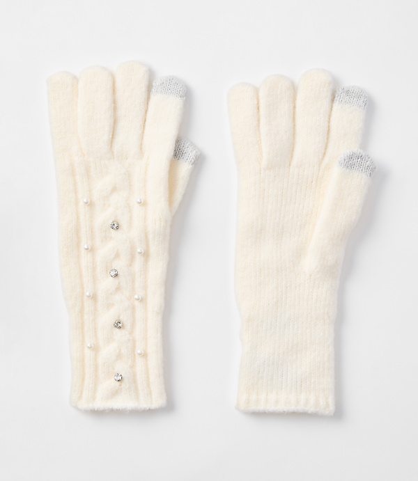 Cream-colored knit gloves, one adorned with pearls and rhinestones, rest on a plain white background.