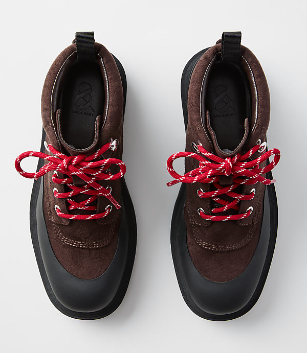 A pair of brown suede hiking boots with red and white laces are displayed against a plain white background.