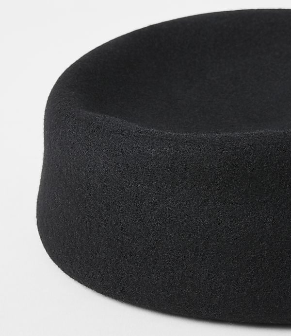 A black felt hat with a rounded crown sits on a plain white background.