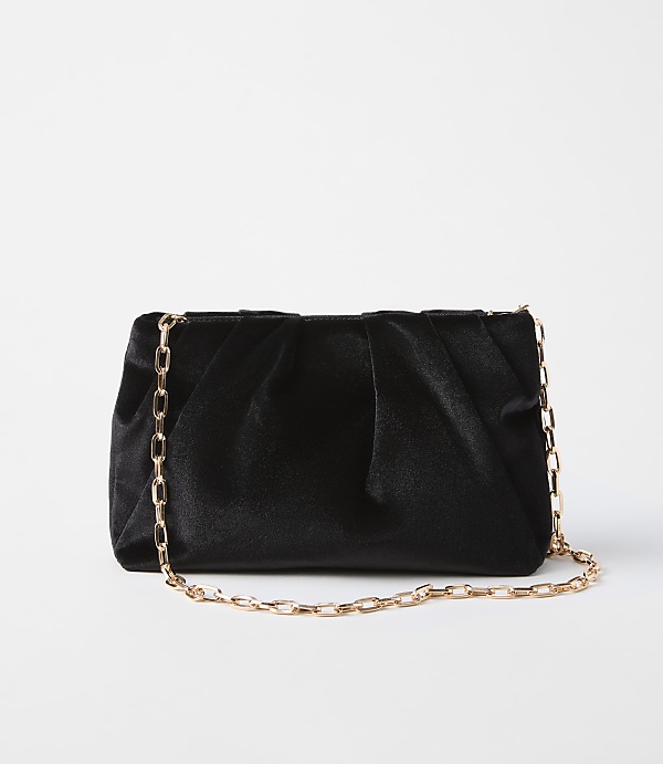 A black velvet clutch with a gold chain strap rests on a plain white background.