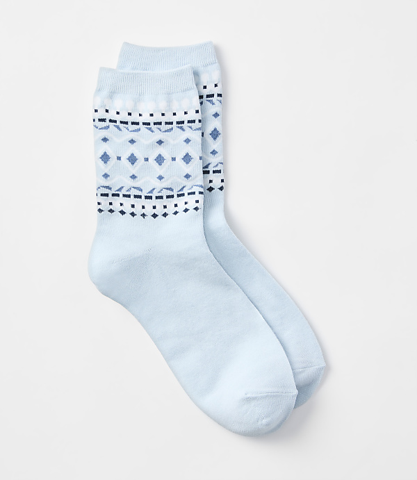 A pair of light blue socks with a fair isle pattern are laid out on a white background.