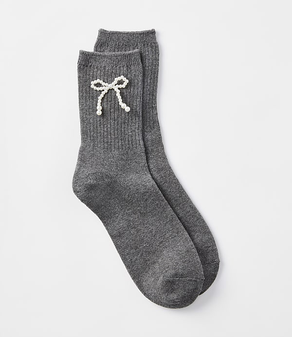A pair of dark gray ribbed socks with a pearl bow detail rests on a plain white background.